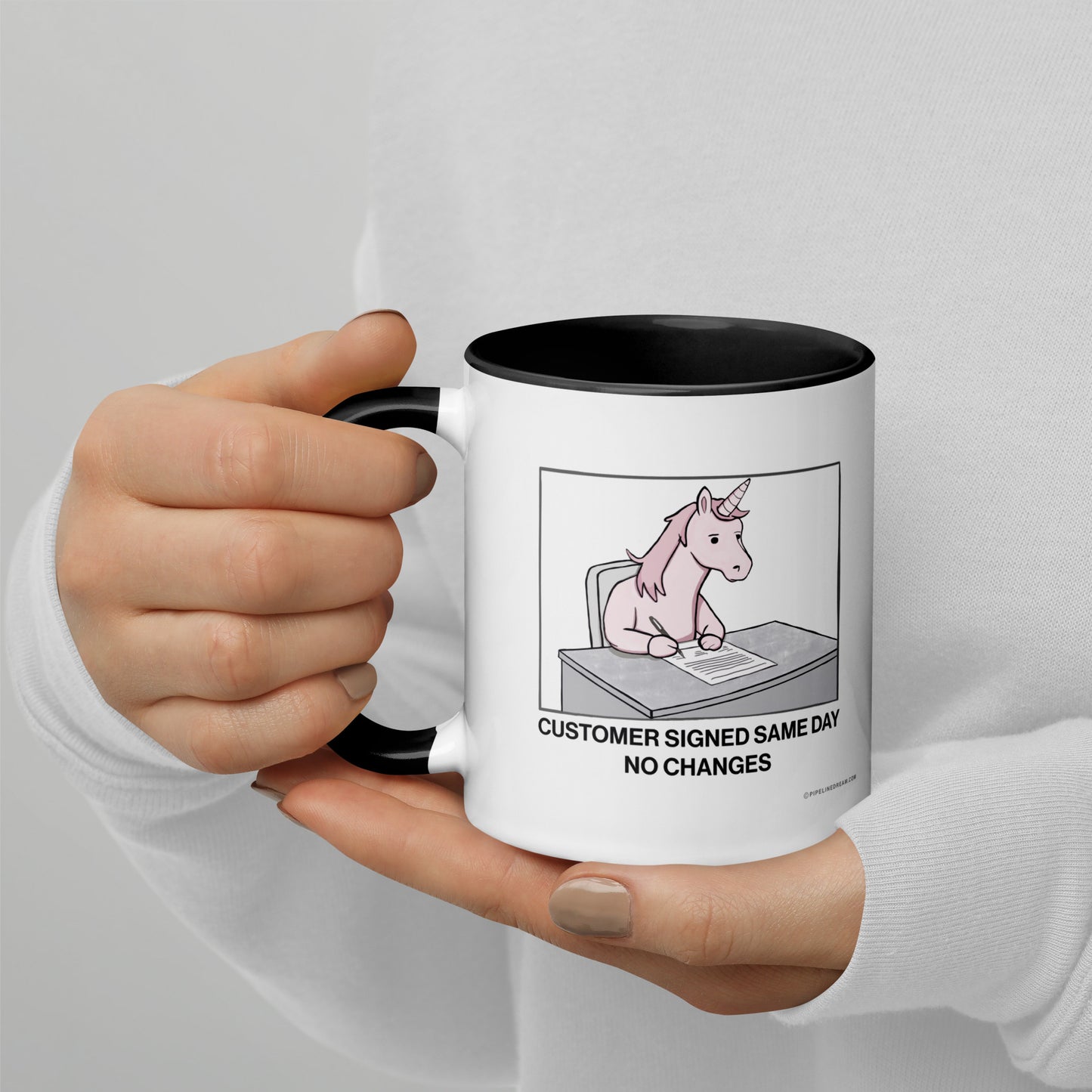 Hand holding sales humor mug about same-day customer approval with no contract changes